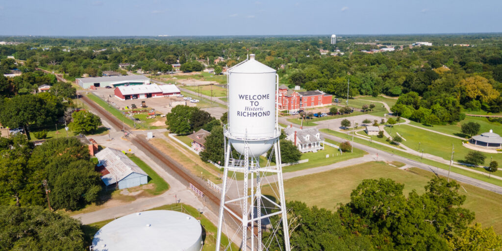 Welcome to Historic Richmond Texas - aerial drone view of white water tower and historic downtown district with red brick buildings and railroad tracks